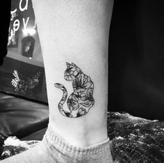 a black and white photo of a cat tattoo on the ankle, with flowers all over it