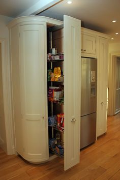 an open pantry in the middle of a kitchen with wood floors and white cabinets,