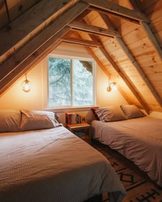 two beds in a loft with wooden walls