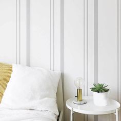 a white bed sitting next to a table with a plant on top of it