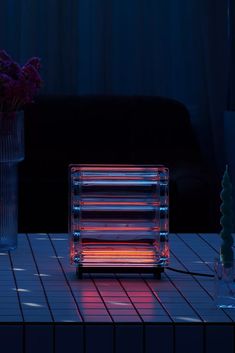 a table topped with a glass vase filled with flowers next to a small heat lamp