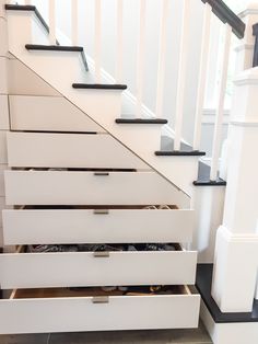 an under stair storage unit with drawers underneath the stairs and below it is a white staircase