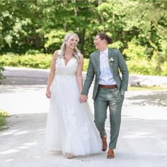 a bride and groom walking down the road holding hands