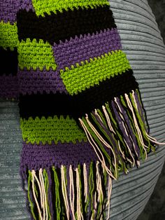 a purple and green knitted scarf sitting on top of a chair