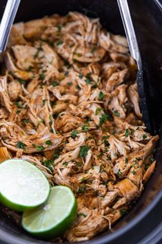 shredded chicken in a slow cooker with limes and cilantro on the side