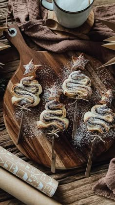 several pastries are on a wooden plate with sugar sprinkles and cinnamon sticks