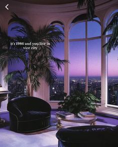 a living room filled with furniture and large windows overlooking the city at night, as well as palm trees