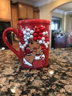 a red coffee mug decorated with white and red ornaments on top of a granite counter