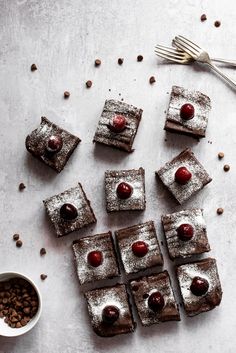 chocolate desserts with cherries and powdered sugar are arranged on a white surface