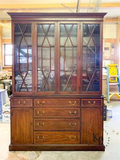 an old wooden china cabinet with glass doors and drawers in a room that is being remodeled