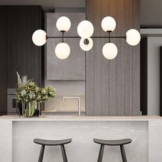 two stools in front of a counter with flowers on it and lights hanging from the ceiling