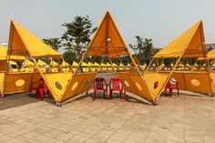 several yellow tents with red chairs around them