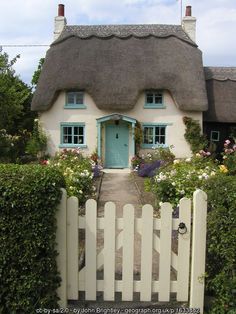 a white house with a blue front door and a picket fence in front of it