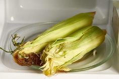 an open ear of corn sitting on top of a glass plate in a microwave oven