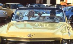 two people sitting in a yellow convertible car