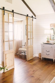 an open door leading to a bedroom with wood floors and white walls, along with a bed