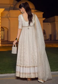 a woman in a white dress is walking down the street with her hand on her hip