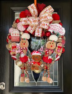 a christmas wreath with gingerbreads, candy canes and other holiday decorations hanging on the front door