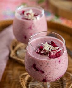 two glasses filled with food sitting on top of a wooden tray next to each other