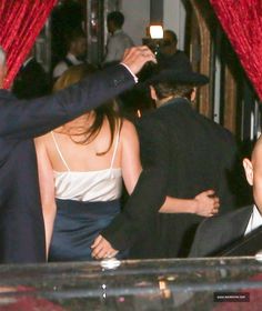 two men and a woman in formal wear at a party