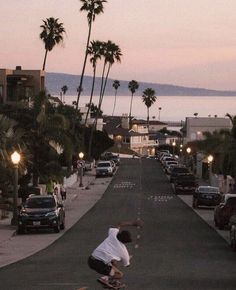 a man riding a skateboard down a street next to palm trees