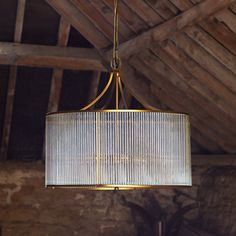 a chandelier hanging from the ceiling in a room with exposed wood beams and brick walls