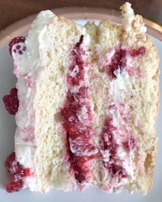 a piece of cake with white frosting and raspberry toppings on a plate