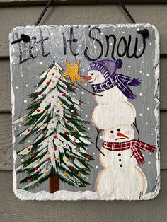 a sign that says let it snow with a snowman and tree