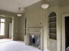 an empty living room with a fireplace and built in bookcases