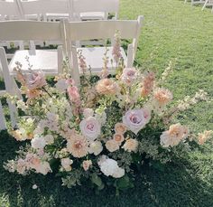 an arrangement of flowers is sitting in the grass at a wedding ceremony with white chairs