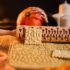 a rolling pin with designs on it sitting next to an apple and other items in the background