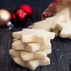 a stack of shortbreads next to christmas ornaments on a wooden surface with baubles in the background