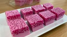 several squares of pink colored soap on a white plate next to a plastic container with red dots