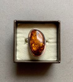 This beautiful sterling silver ring features a large natural Baltic amber stone. The ring's face is about 1.5 cm x 2.5 cm. As of right now, it is size 7.5, but it is adjustable. Amber Stones Sterling Silver Jewelry, Sterling Silver Amber Ring, Amber Oval Cabochon Sterling Silver Ring, Amber Crystal Sterling Silver Ring, Unique Silver Baltic Amber Jewelry, The Ring Face, La Face, Amber Stone, Baltic Amber