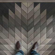 a man standing on top of a wooden floor next to a tiled floor with his feet up