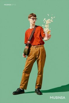 a young man holding a bucket of popcorn and a bag of popcorn while standing in front of a green background