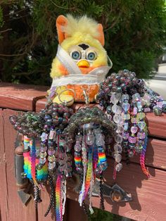 a stuffed animal with lots of beads hanging from it's neck on a wooden fence