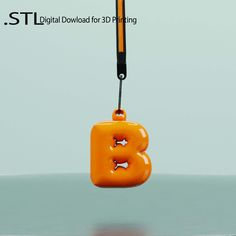 an orange object hanging from a hook on a gray surface with the letter b attached to it