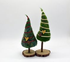 two small trees made out of felt on wooden bases with ribbons and bows around them