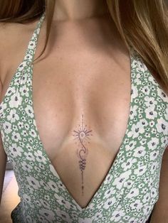 a woman with a tattoo on her chest wearing a green and white dress is looking at the camera