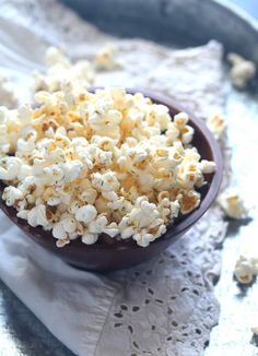 a bowl filled with popcorn sitting on top of a white doily next to a wooden spoon