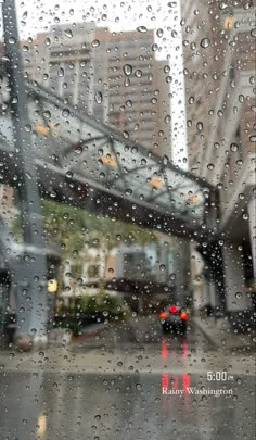 rain drops on the window as cars drive down the street in front of a building