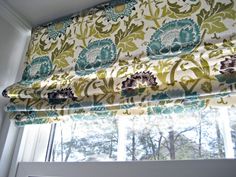 a window with a green and blue flowered valance