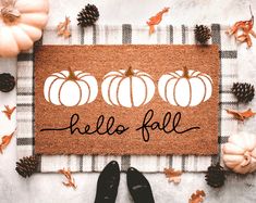 a welcome mat with pumpkins and pine cones