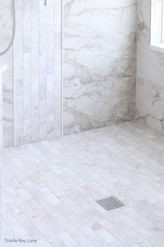 a bathroom with white marble walls and flooring, including a walk in shower area