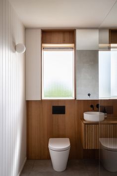 a bathroom with a toilet, sink and mirror next to each other on the wall