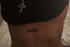 a woman with a cross tattoo on her back and the word straight written in black ink