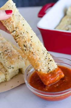 a person dipping some bread into a small bowl with ketchup on the side