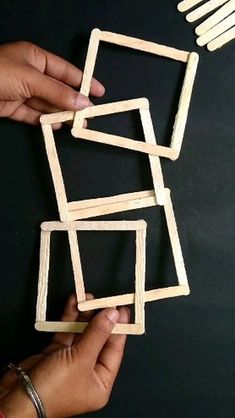 two hands are holding wooden squares on a black surface and one hand is reaching for them