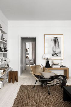 a living room filled with furniture and a painting hanging on the wall above a coffee table